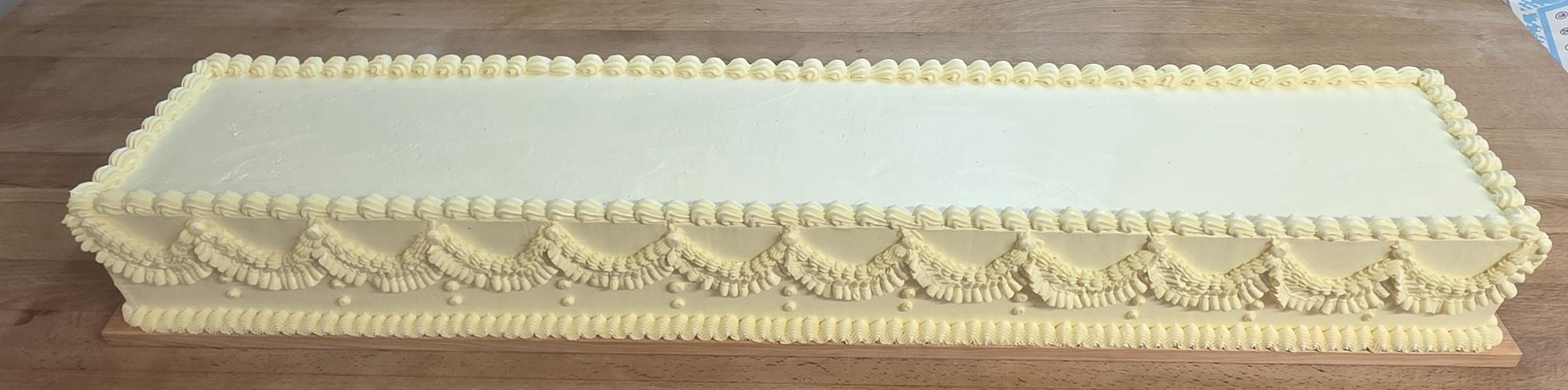 Lange rechteckige Festtorte mit cremefarbener Verzierung