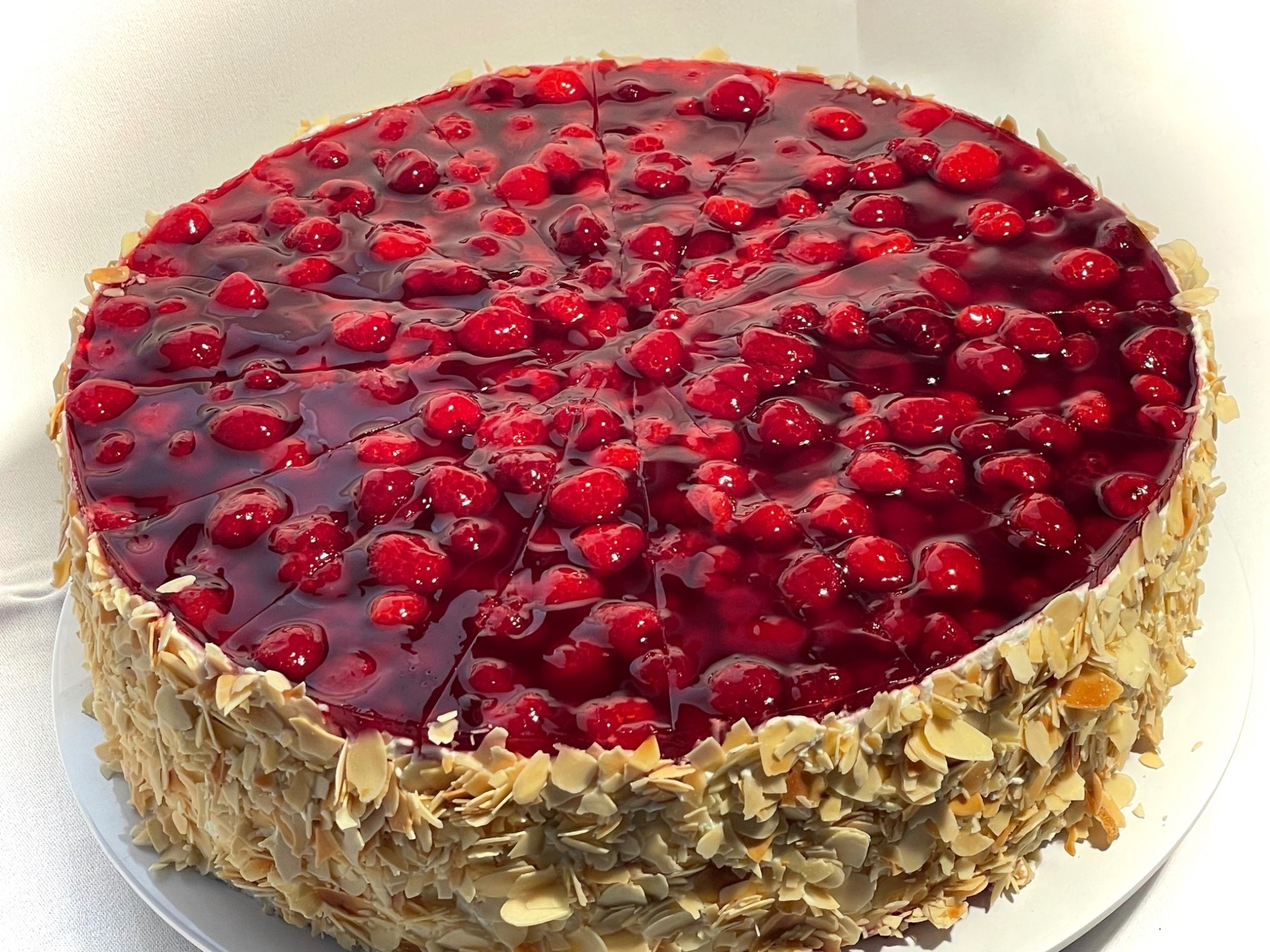 Torte mit rotem Beerenbelag und Mandelrand