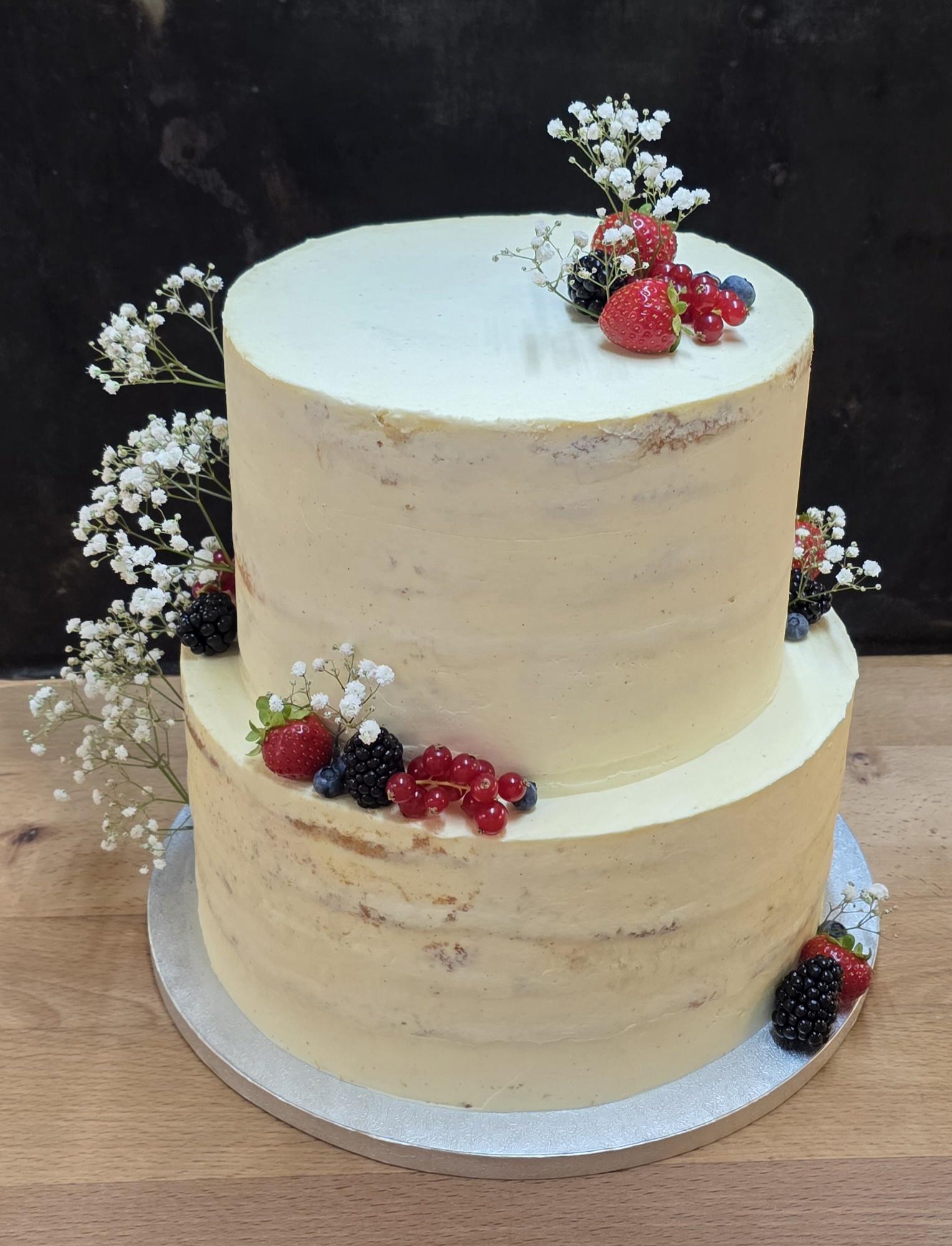 Zweistöckige Torte mit Beeren und weißen Blüten
